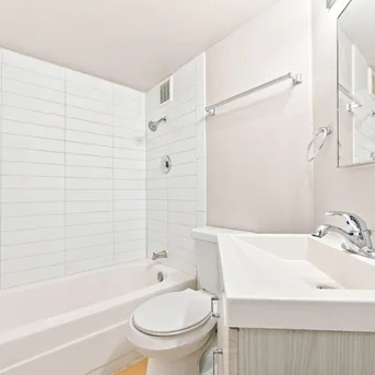 Julian Square Apartments bathroom with tub, vanity, and subway tile